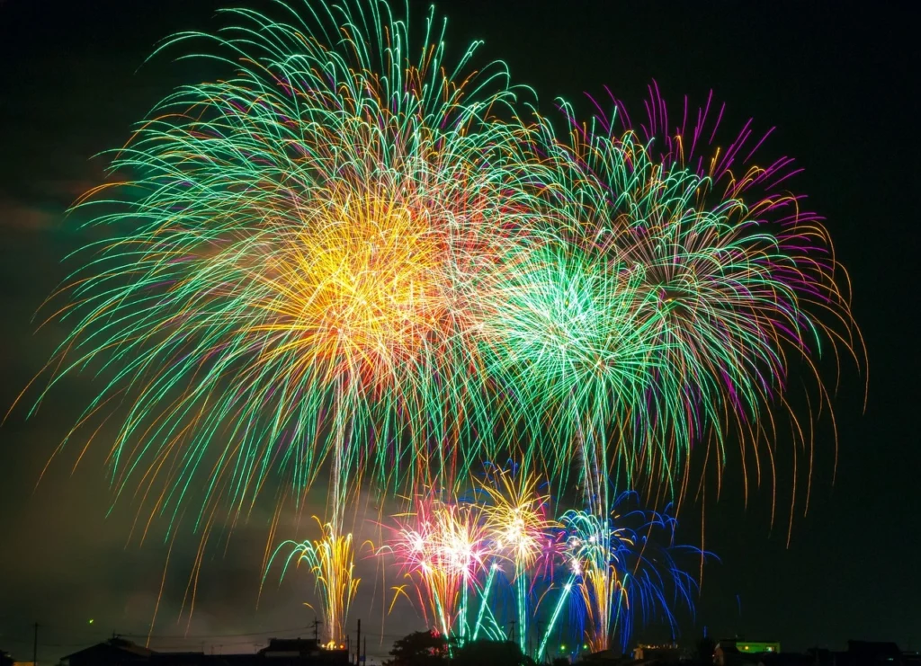 weird festivals around the world A breathtaking display of multi-colored fireworks bursts into the night sky, creating a mesmerizing visual spectacle. Brilliant shades of green, yellow, red, and blue explode above a silhouetted cityscape, illuminating the festival atmosphere with dazzling light trails and radiant energy. This stunning fireworks celebration captures the joy and excitement of cultural festivals around the world, making it a perfect representation of unique global traditions and festive events. Ideal for content focused on weird or extraordinary festivals across the globe, this image evokes a sense of wonder and celebration.